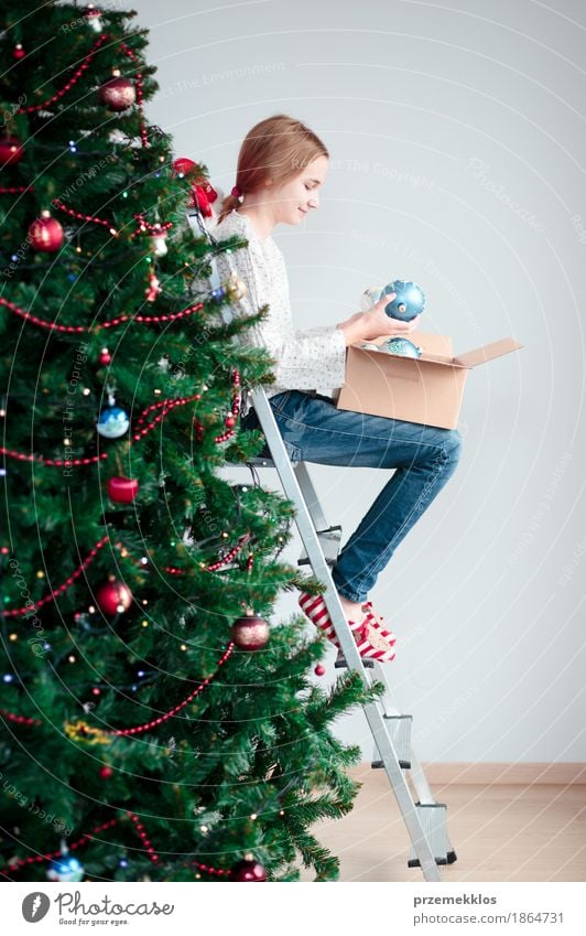 Junges Mädchen, das zu Hause Weihnachtsbaum mit Bällen verziert Lifestyle Freude Dekoration & Verzierung Feste & Feiern Weihnachten & Advent Mensch Kind 1