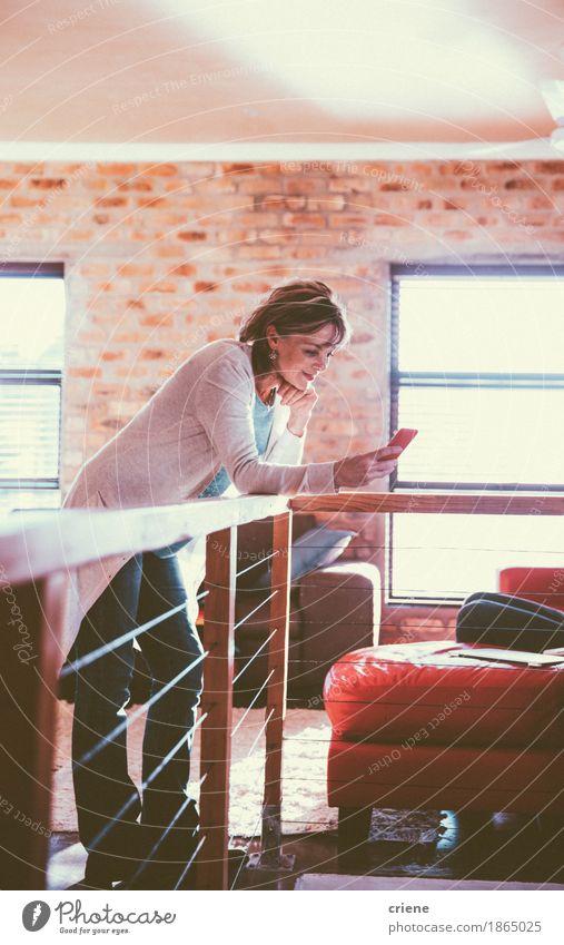 Reife Frau liest Nachricht auf ihrem Smartphone lesen Wohnzimmer Arbeit & Erwerbstätigkeit Arbeitsplatz Büro Business Mittelstand Telefon Handy PDA