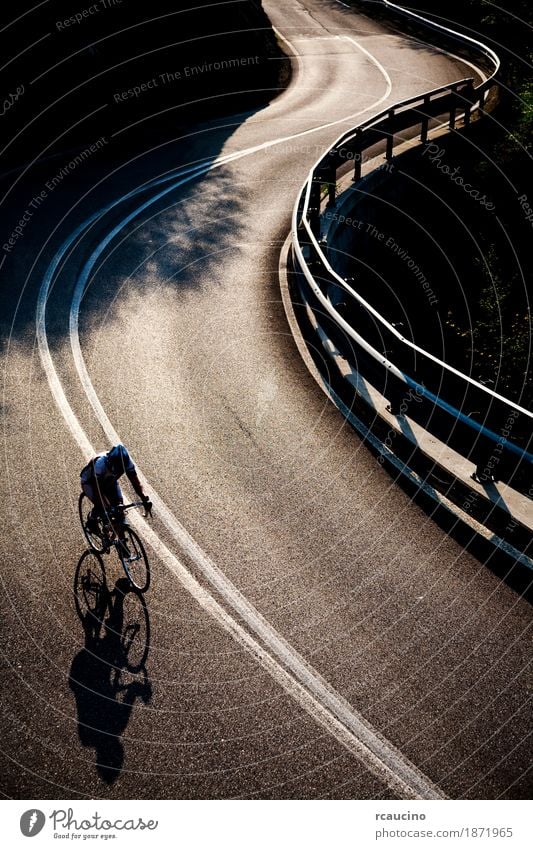 Radfahrer, der entlang eine gepflasterte Gebirgsstraße fährt Erholung Sommer Sport Mann Erwachsene Straße Fitness Einsamkeit Gegenlicht Fahrrad Radfahren