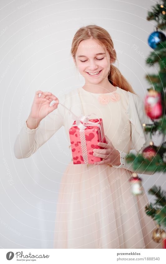 Glückliches Mädchen, welches das Weihnachtsgeschenk steht hinter einem Baum auspackt Lifestyle Feste & Feiern Weihnachten & Advent Kind Mensch 1 8-13 Jahre