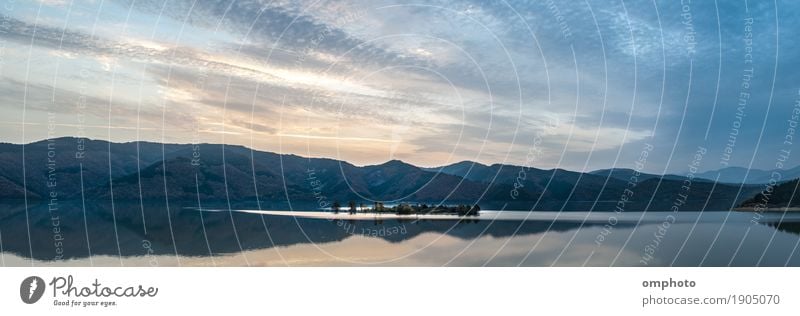 Weite Panoramalandschaft eines Bergsees mit einer kleinen Insel in der Mitte Winter Berge u. Gebirge Natur Landschaft Wasser Himmel Wolken Sonnenaufgang