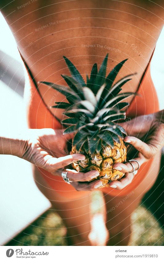 Junge Frauen im Bikini, der Ananas hinter ihr zurück hält Frucht Lifestyle Stil Freude Erholung Schwimmbad Sommer Sonnenbad Jugendliche Erwachsene 18-30 Jahre