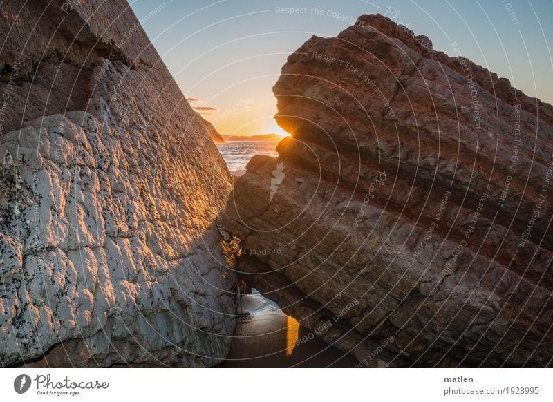 Blinzel Umwelt Natur Landschaft Wasser Himmel Wolkenloser Himmel Horizont Sonne Sonnenlicht Schönes Wetter Felsen Küste Strand Meer exotisch blau braun grau