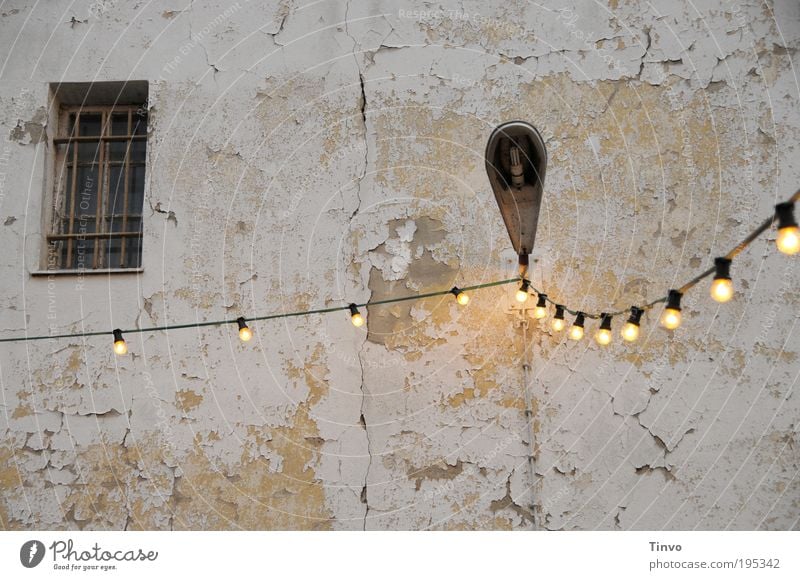 Illuminierte Lampe Mauer Wand Fassade Fenster alt dreckig Lichterkette Elektrizität Glühbirne Laterne Außenbeleuchtung vergittert Putzfassade abblättern