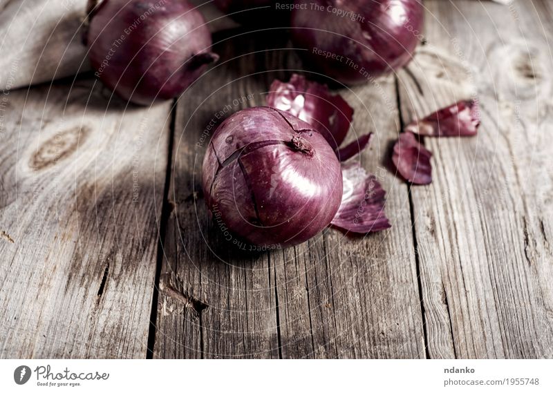 Rote Zwiebeln in der Hülse auf der grauen Holzoberfläche Gemüse Vegetarische Ernährung Pflanze alt dunkel frisch braun rot reif Knolle organisch Salatbeilage