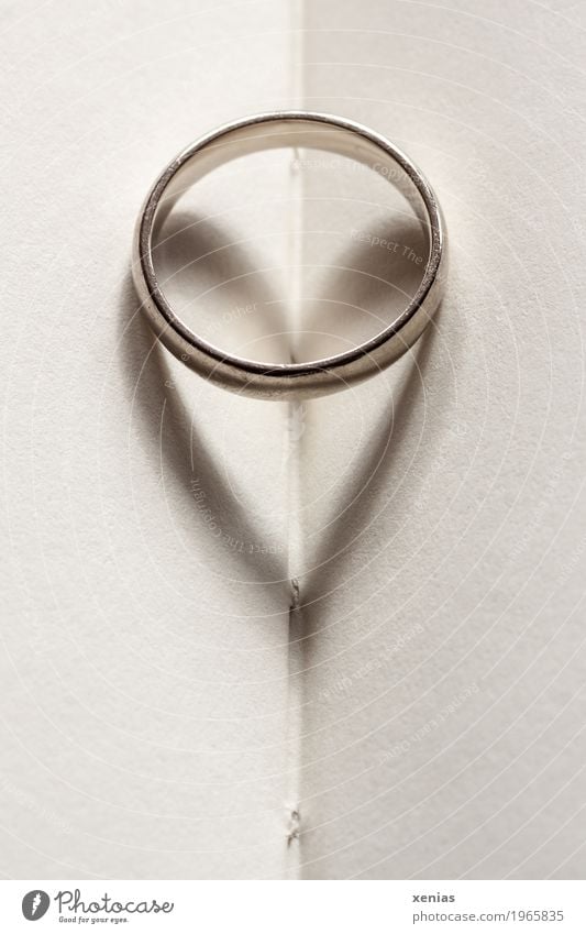 Ring mit Herz als Schatten liegt auf Papier Buch Ehering Schmuck Hochzeit Buchseite Gold silber weiß Liebe Zusammenhalt Goldlegierung herzförmig Postkarte