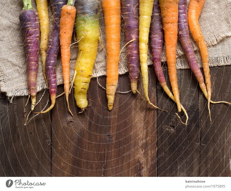 Frische organische Regenbogenkarotten auf einem Holztisch Gemüse Ernährung Vegetarische Ernährung frisch braun gelb Möhre Landwirt Lebensmittel Ernte Gesundheit