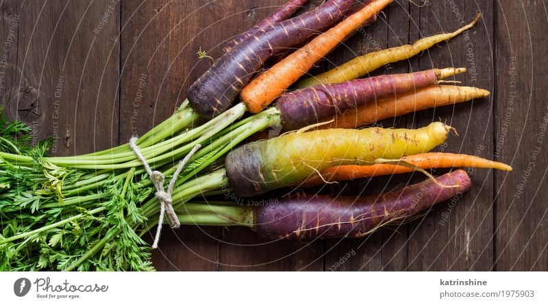 Frische organische Regenbogenkarotten auf einem Holztisch Gemüse Ernährung Vegetarische Ernährung Diät frisch braun gelb Möhre Landwirt Lebensmittel Ernte