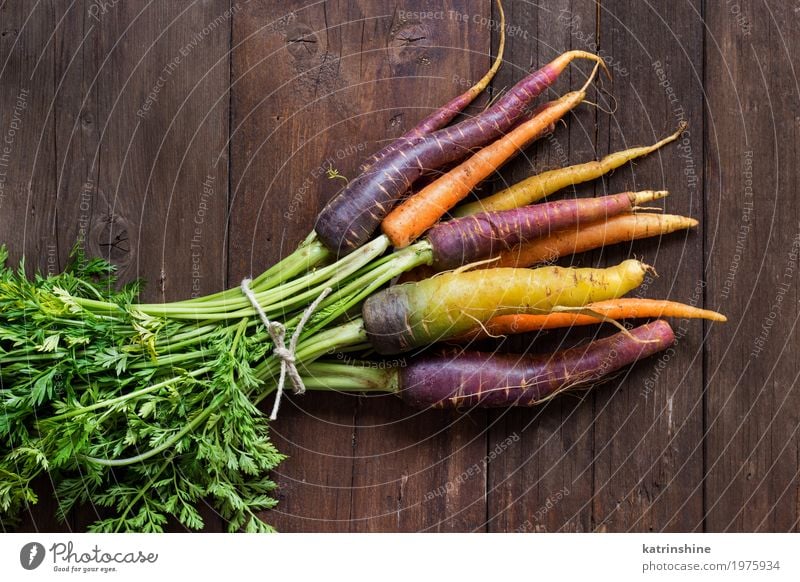 Frische organische Regenbogenkarotten mit Blättern auf einem Holztisch Gemüse Ernährung Vegetarische Ernährung frisch braun gelb Möhre Landwirt Lebensmittel