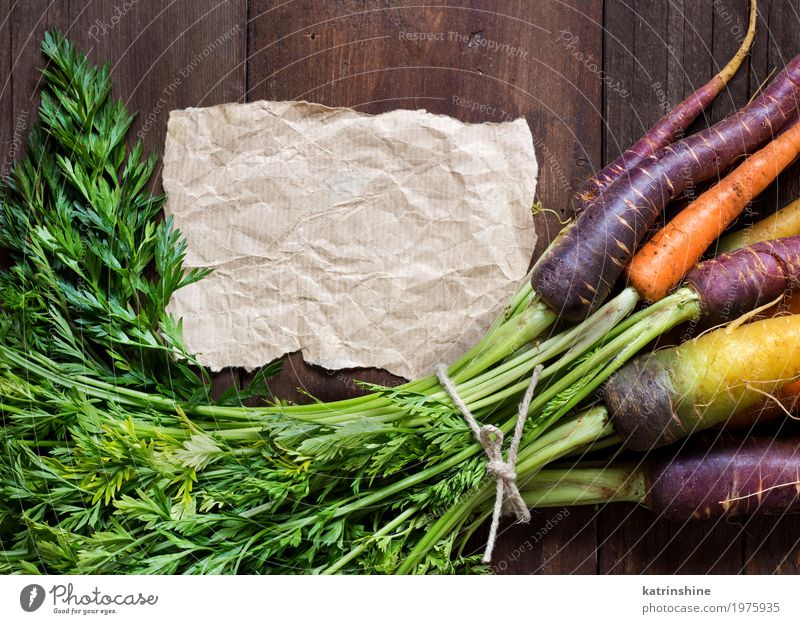 Frische organische Regenbogenkarotten und Kraftpapier auf Holz Gemüse Ernährung Vegetarische Ernährung Papier schreiben frisch braun gelb Möhre Landwirt