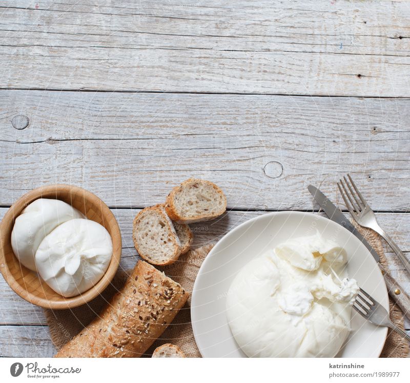 Italienischer Käse Burrata mit Brot auf einem hölzernen Hintergrund Ernährung Vegetarische Ernährung Italienische Küche Teller Schalen & Schüsseln Messer Gabel