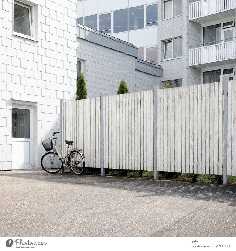 parkplatz Pflanze Haus Bauwerk Gebäude Architektur Fassade Balkon Fenster Tür Fahrrad ästhetisch Sauberkeit grau weiß Farbfoto Außenaufnahme Menschenleer Tag