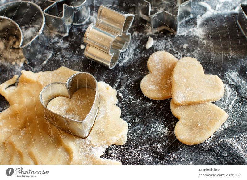 Schließen Sie oben von den Plätzchenschneidern in einem Teig auf einer dunklen Tabelle Teigwaren Backwaren Dessert Küche Herz machen backen Bäckerei Biskuit