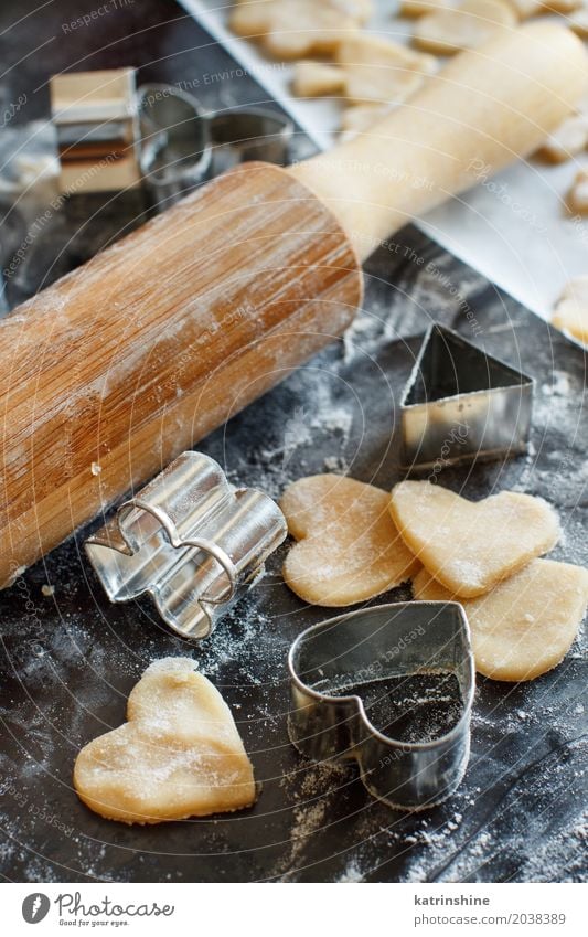 Schließen Sie oben von den Plätzchenschneidern und Nudelholz auf einer dunklen Tabelle Teigwaren Backwaren Dessert Küche Herz machen backen Bäckerei Biskuit