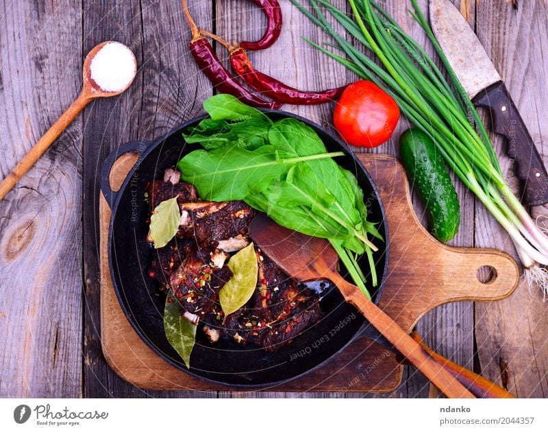 Gebratene Schweinerippchen in Gewürzen Fleisch Gemüse Kräuter & Gewürze Pfanne Holz frisch lecker grün rot schwarz Schweinefleisch Rippen Gitter Tomate Zwiebel