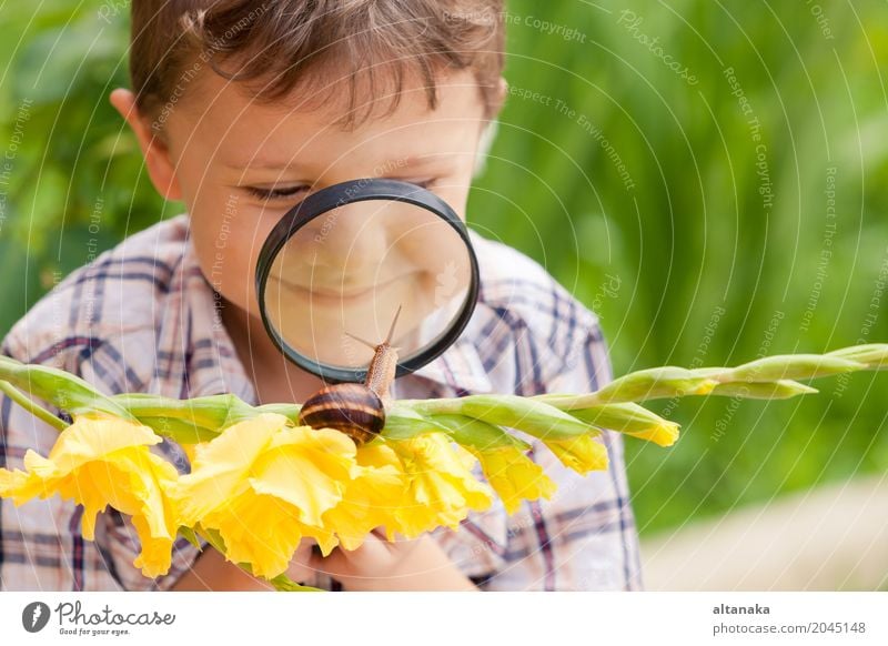 Glücklicher kleiner Junge, der im Park mit Schnecke zur Tageszeit spielt. Lifestyle Freude Erholung Freizeit & Hobby Freiheit Sommer Garten Kind Schule Mensch