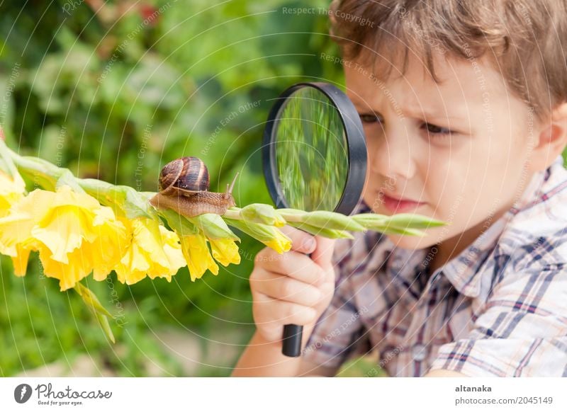 Glücklicher kleiner Junge, der im Park mit Schnecke zur Tageszeit spielt. Lifestyle Freude Erholung Freizeit & Hobby Freiheit Sommer Garten Kind Schule Mensch