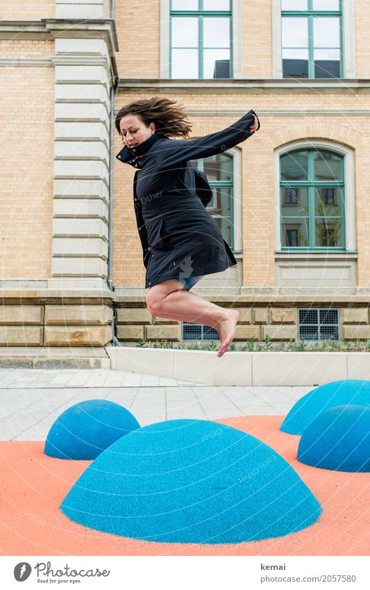 Frau im Mantel springt barfuss auf blauen Gummihügeln Lifestyle Leben Wohlgefühl Zufriedenheit Freizeit & Hobby Spielen Spielplatz Ferien & Urlaub & Reisen