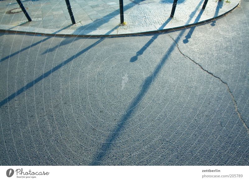 Kurve Straße Straßenverkehr Asphalt Bürgersteig Bordsteinkante Poller Grenze Geländer Sonne Schatten Abend Linie rund Parkplatz Textfreiraum Menschenleer