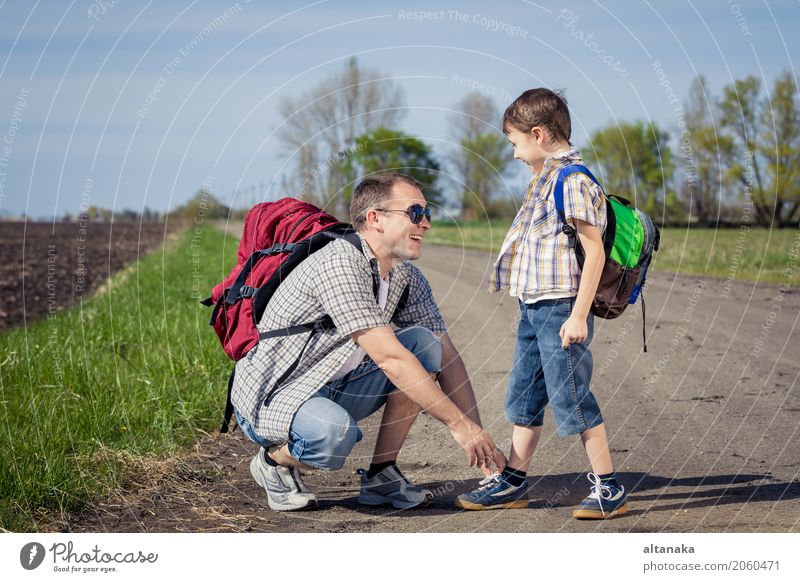 Vater und Sohn, die auf die Straße zur Tageszeit gehen. Lifestyle Freude Glück Freizeit & Hobby Ferien & Urlaub & Reisen Tourismus Ausflug Abenteuer Freiheit