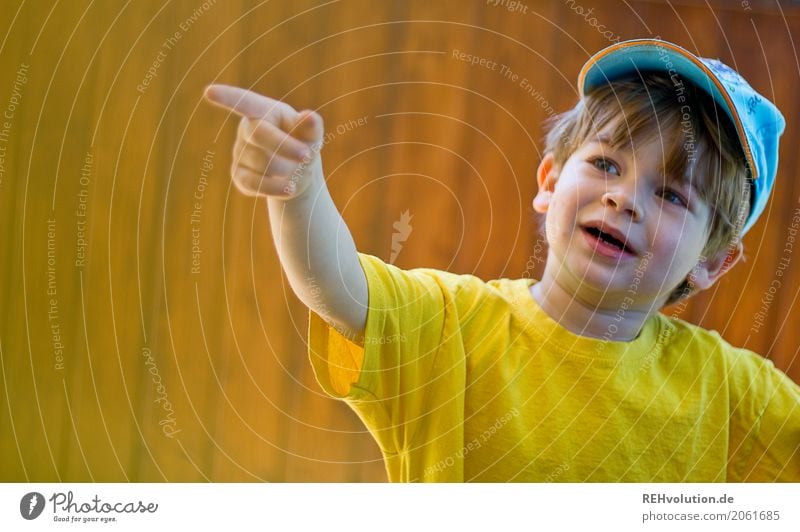 Kind zeigt auf etwas Mensch Kleinkind Junge Kindheit Gesicht 1 1-3 Jahre Sommer T-Shirt Mütze Holz Lächeln sprechen authentisch klein natürlich niedlich gelb