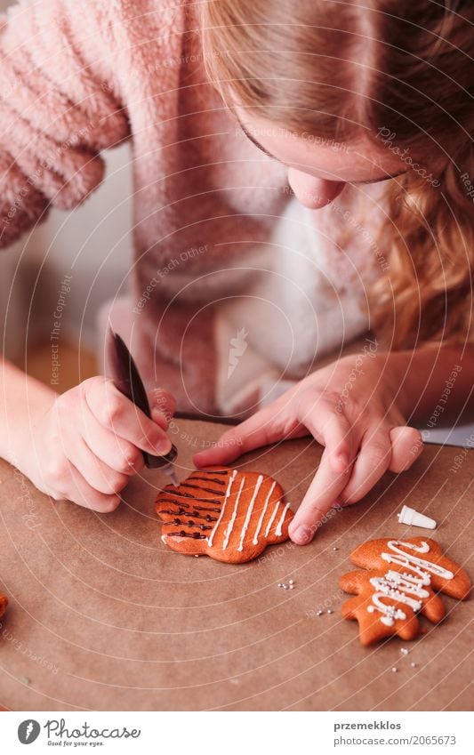 Mädchen, das Weihnachtslebkuchenplätzchen mit Schokolade verziert Lifestyle Dekoration & Verzierung Tisch Feste & Feiern Weihnachten & Advent Mensch 1