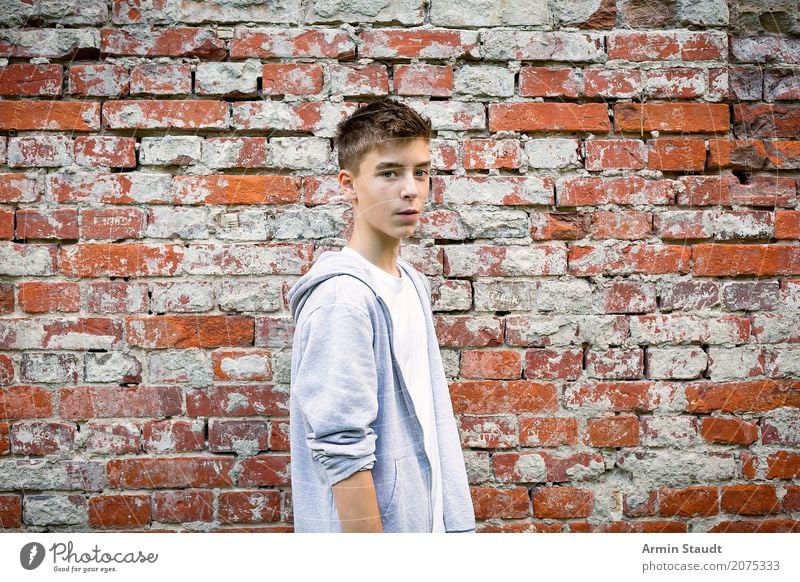 portrait of a cool teenager with hoodie in front of a brick wall Lifestyle Stil Leben Zufriedenheit Sinnesorgane Mensch maskulin Junger Mann Jugendliche