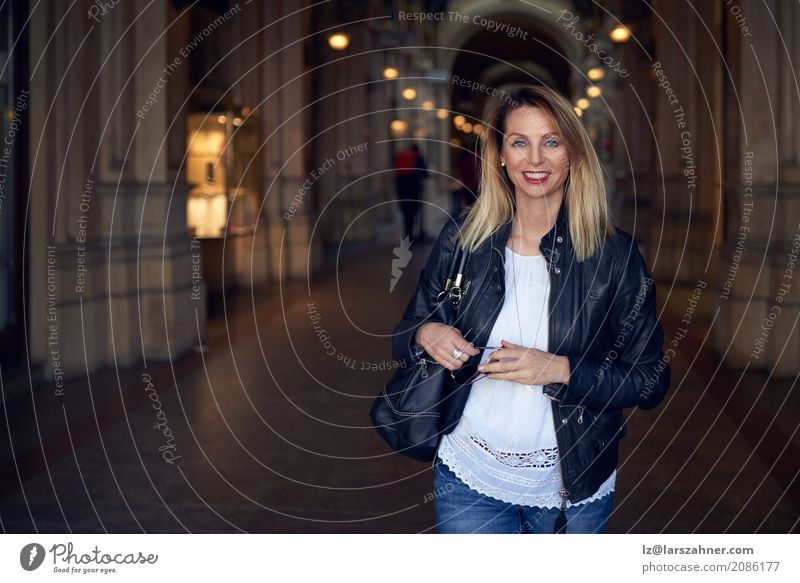 Attraktive modische Frau, die durch einen Säulengang geht Glück Sommer Erwachsene 1 Mensch 30-45 Jahre Jacke Sonnenbrille blond Lächeln stehen trendy attraktiv