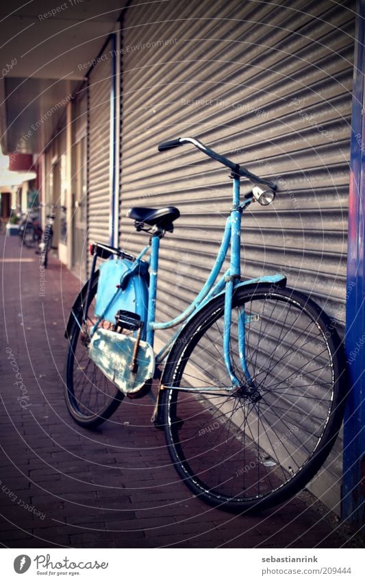 Hollandrad Fahrrad Tür Garagentor Tor Verkehr Verkehrsmittel Stein Metall alt dreckig dunkel Originalität retro trist Stadt blau Farbfoto Außenaufnahme