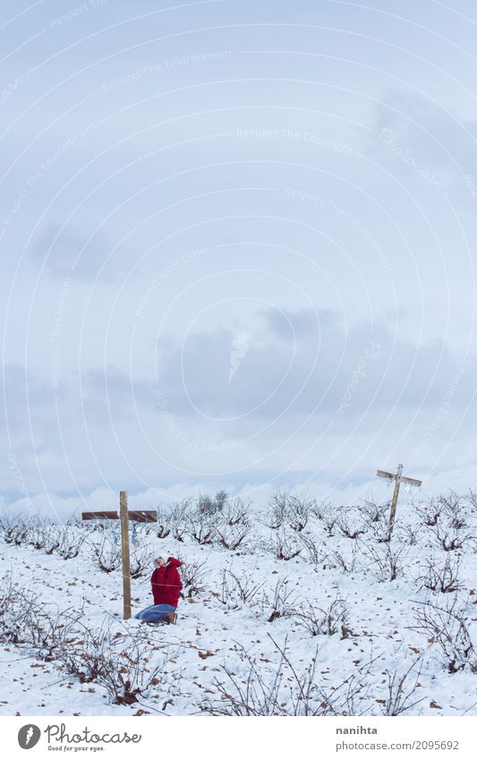 Junge Frau, die in einem Friedhof am Winter betet Mensch feminin Jugendliche 1 18-30 Jahre Erwachsene Natur Landschaft Himmel Wolken Horizont Klima Wetter