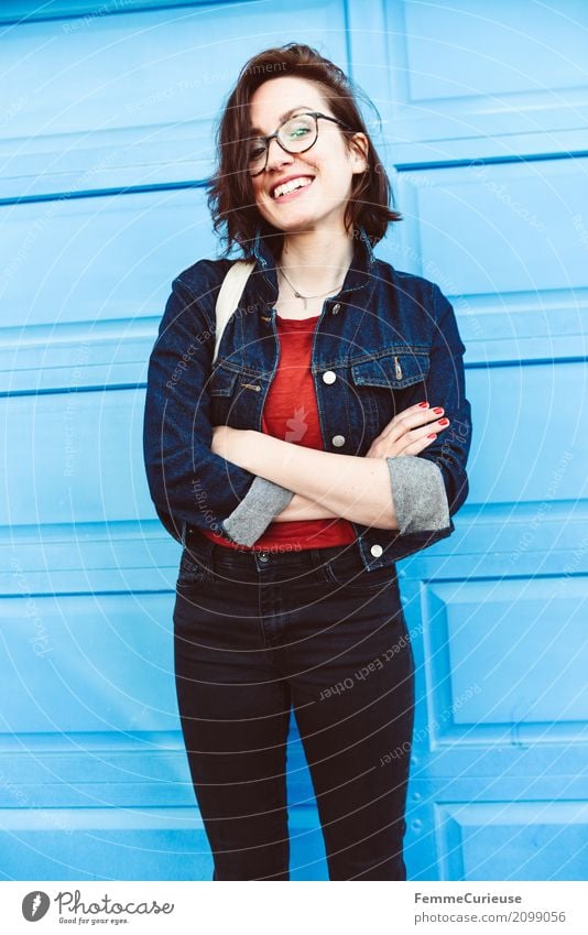 Young woman in front of blue wall feminin Junge Frau Jugendliche Erwachsene 1 Mensch 18-30 Jahre 30-45 Jahre Freude Glück Gute Laune positiv Jeansjacke Mode