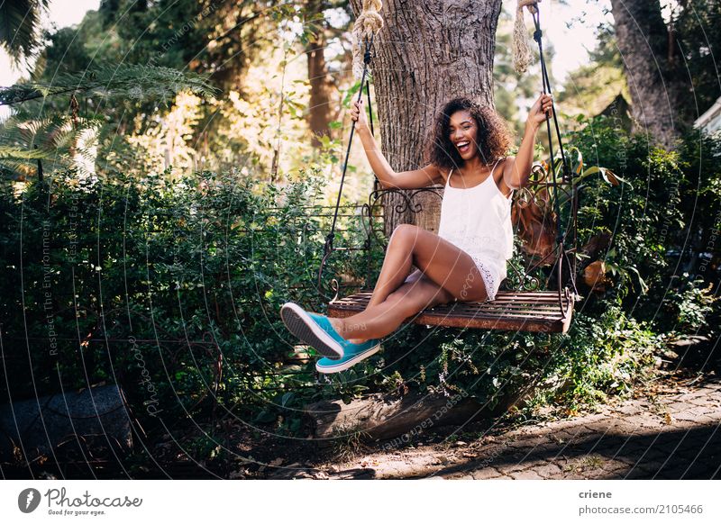 Afrikanerin, die auf Schwingen im Garten im Sommer sitzt Lifestyle Freude Glück Freizeit & Hobby Sommerurlaub Sonne Mensch feminin Junge Frau Jugendliche 1