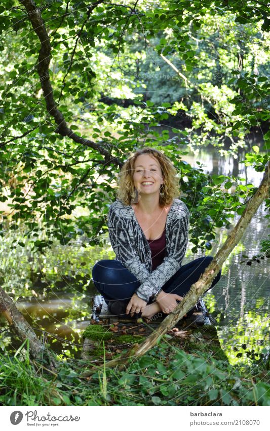 Lebenselixier l Natur feminin Frau Erwachsene 1 Mensch Landschaft Urelemente Wasser Sonne Pflanze Sträucher Seeufer Teich lachen sitzen Fröhlichkeit Gefühle