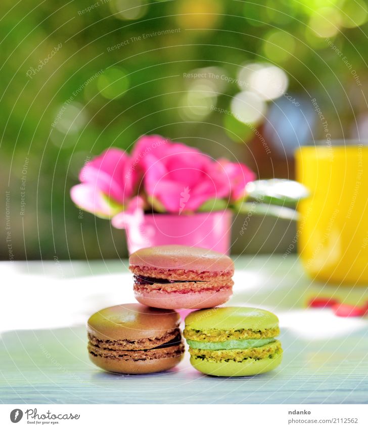 bunte Makronen Dessert Süßwaren Tasse Tisch Blume Holz Essen hell braun gelb grün rosa weiß Macaron Biskuit Roséwein Lebensmittel geschmackvoll sonnig