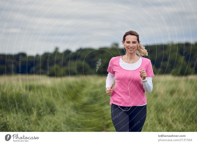 Nette Frau, die durch Feld läuft Lifestyle Gesicht Sommer Musik Sport Joggen PDA Erwachsene 1 Mensch 30-45 Jahre Natur Herbst blond Fitness hören Lächeln