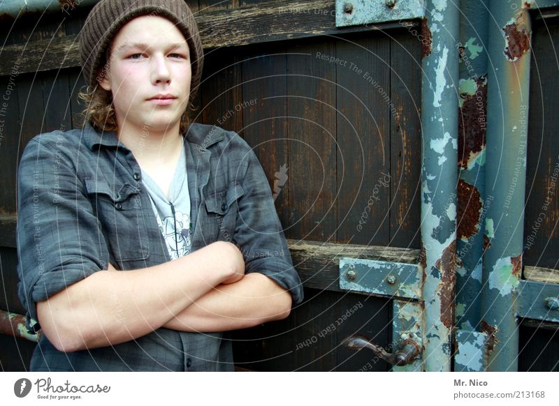 türsteher maskulin Junger Mann Jugendliche Arme Hemd Mütze Coolness Kraft Sicherheit Eingang Eingangstor Schüler verweigern stark Holztor Blick Kontrolle