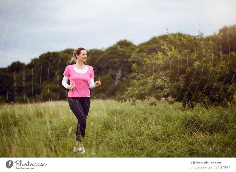 Geeignete Frau von mittlerem Alter, die durch ein Feld geht Lifestyle Glück Sommer Sport Telefon Handy Erwachsene 1 Mensch 30-45 Jahre Natur Wege & Pfade blond