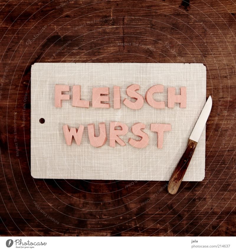 quatschfoto Lebensmittel Fleisch Wurstwaren Ernährung Fingerfood Messer Schneidebrett Holz Schriftzeichen lustig braun grau rosa Fleischwurst Farbfoto