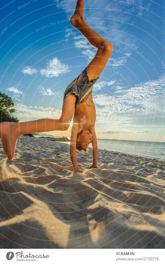 Hübscher achtjähriger Junge am tropischen Strand von Koh Samui, heller und farbenfroher Sonnenuntergang hinter ihm Lifestyle Freude Spielen Kinderspiel Freiheit