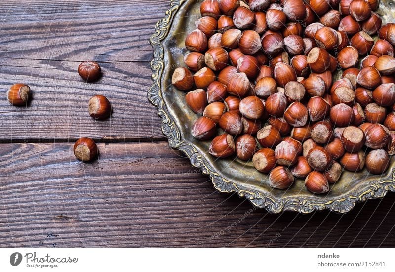 Haselnüsse auf einer Eisenplatte Frucht Ernährung Vegetarische Ernährung Teller Tisch Natur Herbst Holz alt Essen frisch natürlich oben stark braun Hintergrund