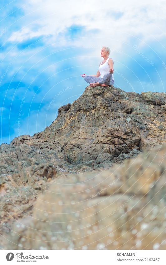 Eine schöne reife alte Frau sitzt auf einer Klippe und macht Yoga. Meditation feminin Erwachsene Weiblicher Senior Großmutter 1 45-60 Jahre Natur Landschaft