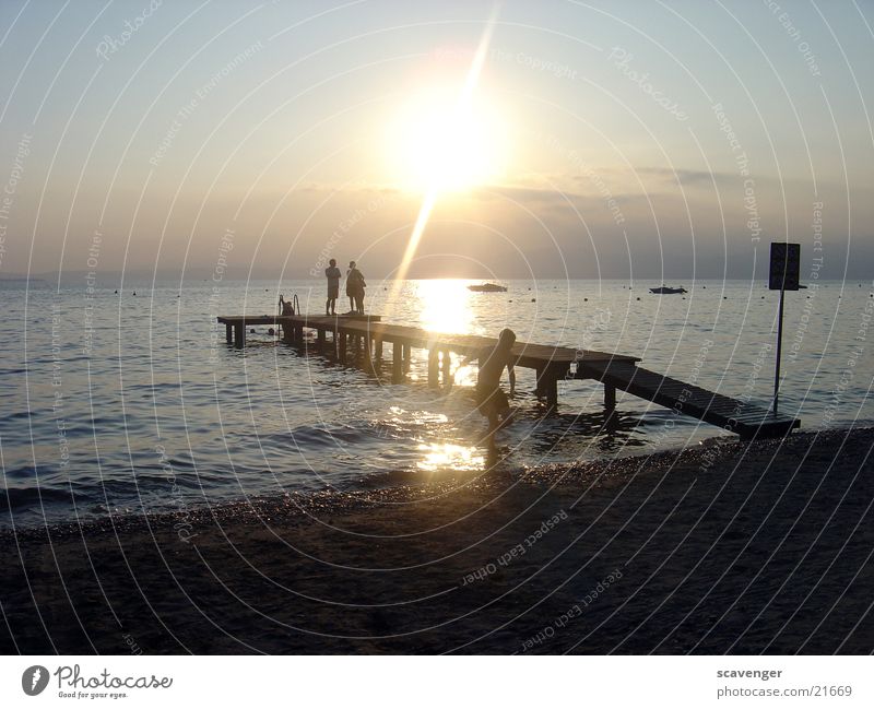 Sonnenuntergang Gardasee Sonnenstrahlen weiß Licht Abendsonne Sonnenaufgang dunkel See Wellen Wasserfahrzeug Strand Steg Horizont Holz Romantik Beleuchtung blau