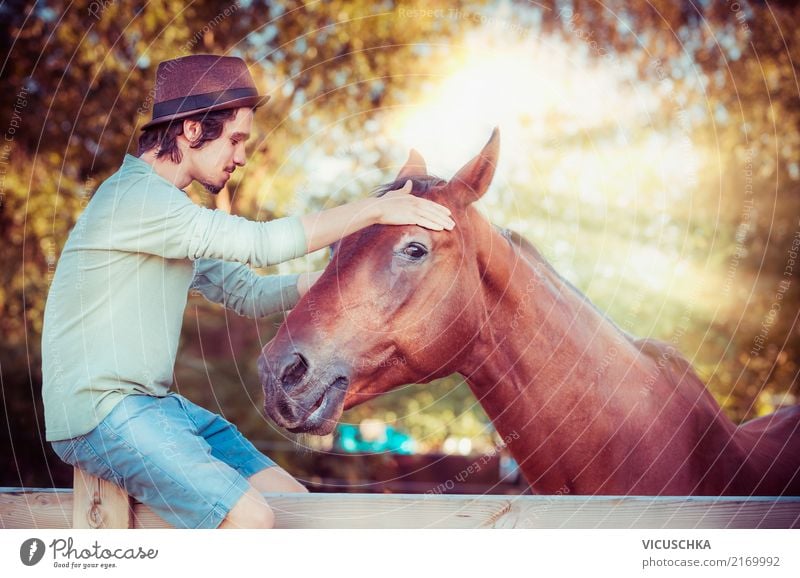 Pferd und junger Mann mit Hut Lifestyle Winter Mensch Junger Mann Jugendliche Natur Schönes Wetter Gefühle Design sentimental Kommunizieren Umarmen Farbfoto