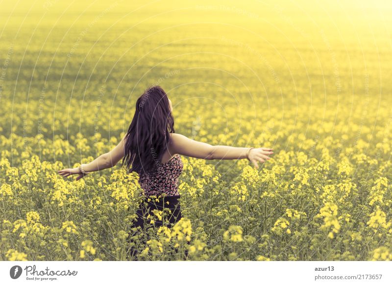 Schöne junge Frau im Sommer auf gelber Wiese aus Raps bis zum Horizont. Hübsches Mädchen mit Lebensfreude geniesst die Sonnenschein Pause und das Leben. Erholung und Energie tanken vom Zeit Stress in der Umwelt und Natur Idylle. Ausgestreckte Arme.