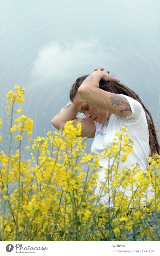 Junge tätowierte Frau mit Rastas im blühenden Raps Junge Frau Rapsfeld Tattoo Jugendliche Mensch Frühling Rapsblüte langhaarig Rastalocken Denken Erholung