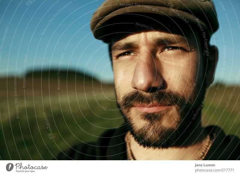 Hat Trick maskulin 1 Mensch blau braun grün Mütze Bart Wiese Himmel Schönes Wetter Auge Ferne nachdenklich Farbfoto Außenaufnahme Textfreiraum links Dämmerung