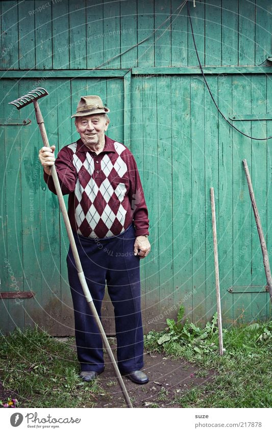 Innerlich tobt er Freizeit & Hobby Garten Gartenarbeit Mensch maskulin Männlicher Senior Mann Großvater 1 Hose Hut alt Freundlichkeit grün Gärtner Wand Rechen