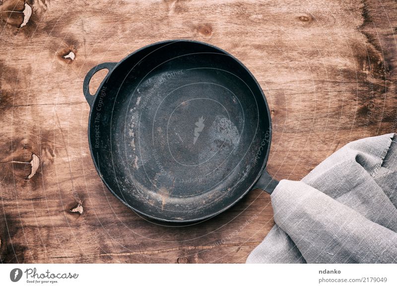 Runde schwarze Gusseisenpfanne Pfanne Tisch Küche Holz Metall Stahl alt grau braten leer Lebensmittel Hintergrund Gerät Utensil Aussicht Essen zubereiten