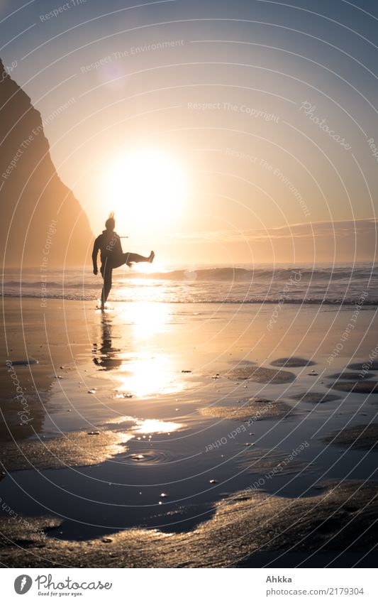 Sportliche Aktivität eines jungen Menschen am Strand vor einer niedrigen Sonne im Gegenlicht mit Bergen sportlich Fitness Leben harmonisch Wohlgefühl