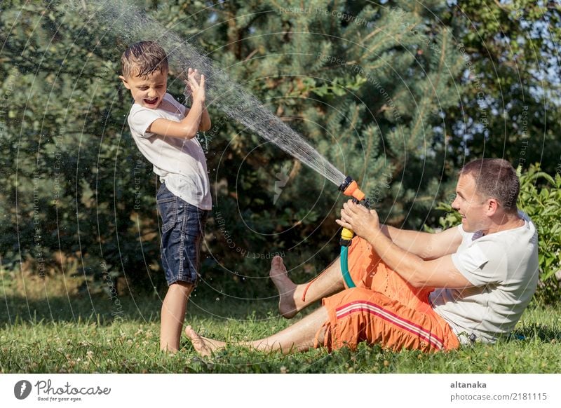 Glücklicher Vater und Sohn spielen im Garten zur Tageszeit. Menschen, die Spaß im Freien haben. Konzept der glücklichen Familie. Lifestyle Freude